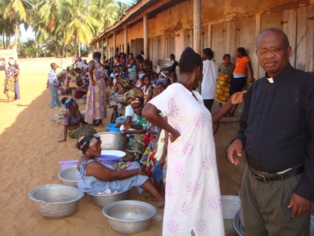 Villagers waiting for the food distribution to begin, with Fr. Patrick standing nearby.